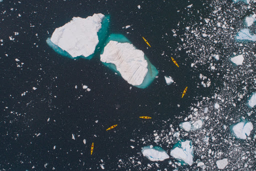 Aerial view of Seabourn passengers on kayaks amongst a variety of icebergs.