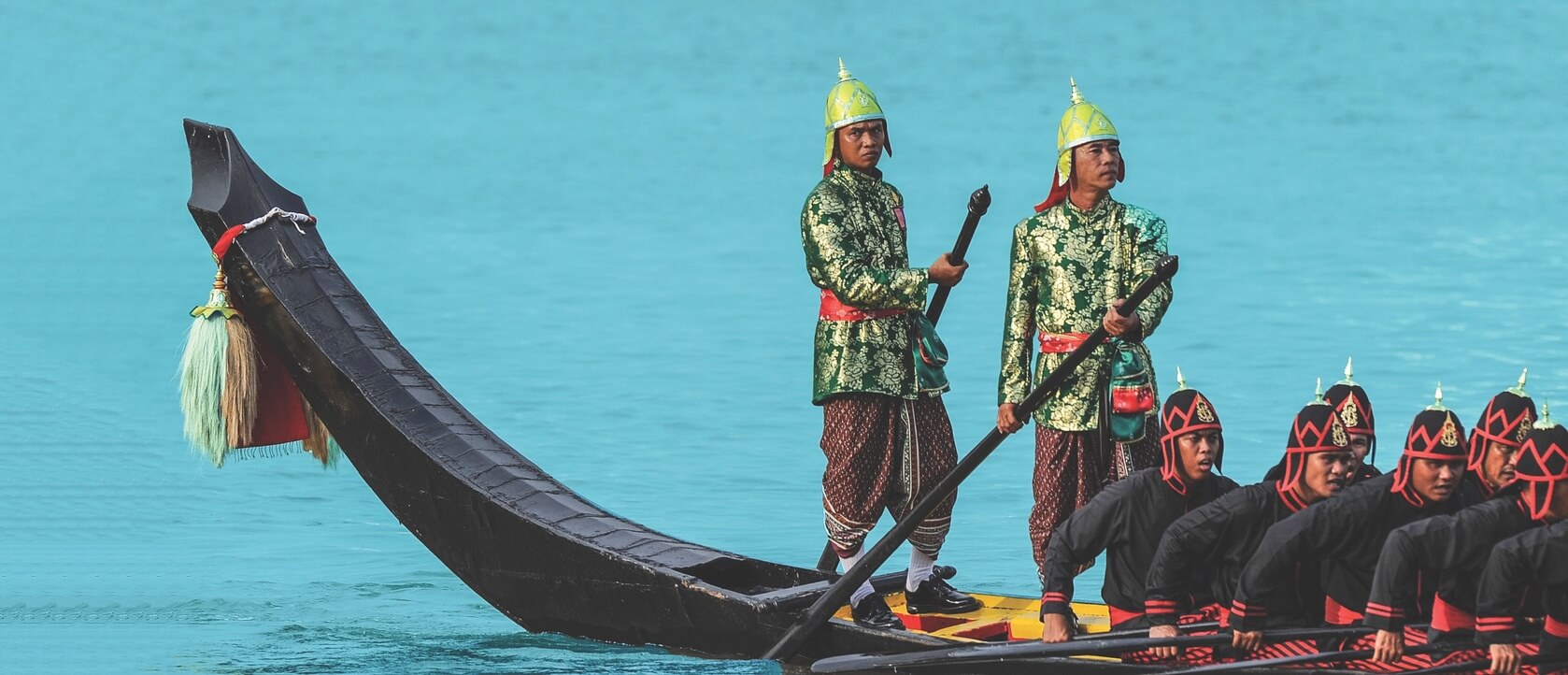 Locals in Bangkok dressed in traditional wear in an ancient styled canoe rowing down the canal