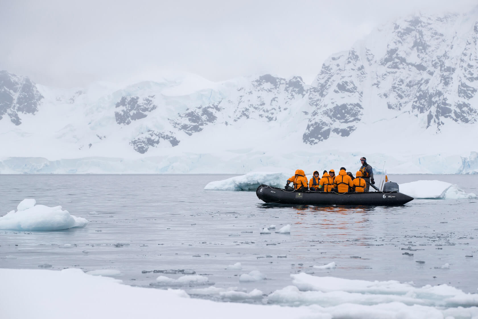 An inflatable boat, with Seabourn passengers, sets on an excursion amongst ice cliffs.
