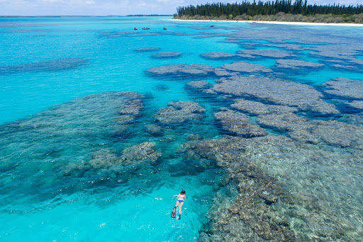 Seabourn passenger snorkles freely amongst coral in crystal clear turquoise water.